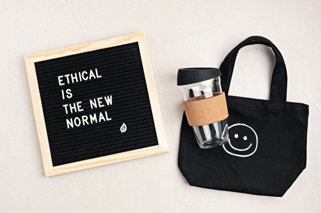 Ethical is the new normal letterboard text. Black organic cotton eco bag and reusable coffee cup